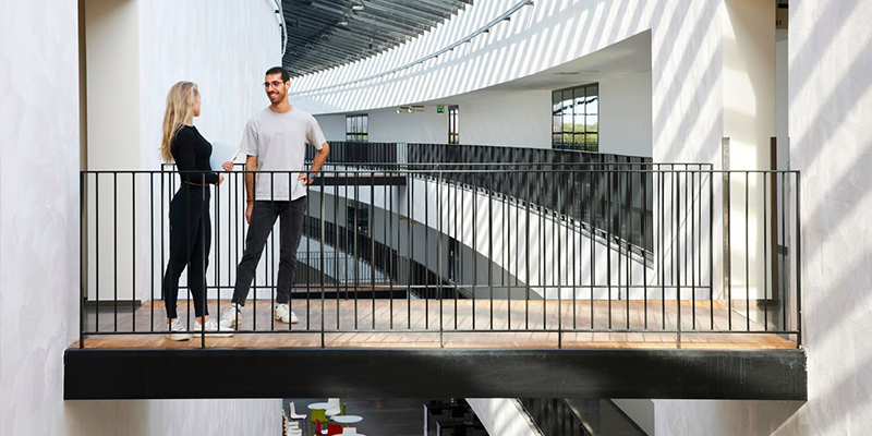 Students stand on a walking bridge in AlbaNova