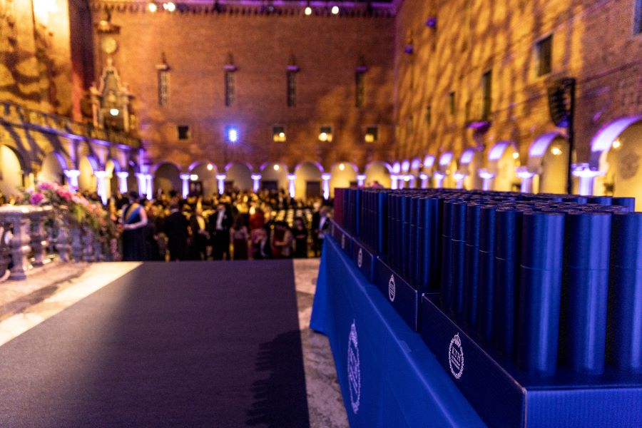 Bilden visar ett bord med doktorsdiplom samt en överblick över Blå hallen.