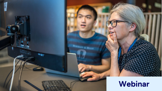 Bibliotekarie hjälper student framför dator