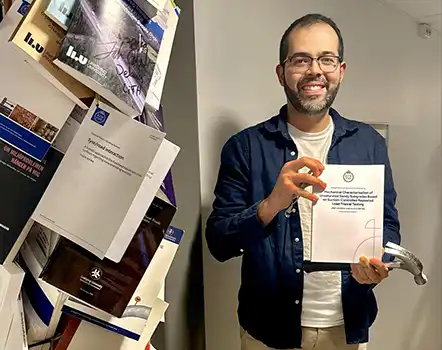 En man håller en avhandling och en hammare