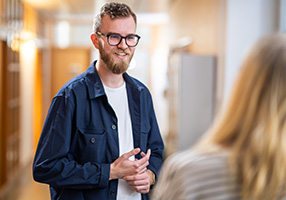 Två personer står i en korridor och pratar