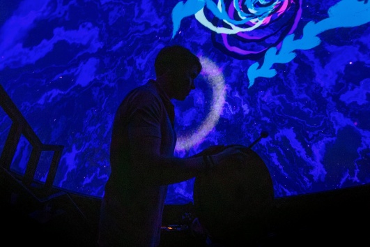 Erasmus playing a drum with the dome projection in the background