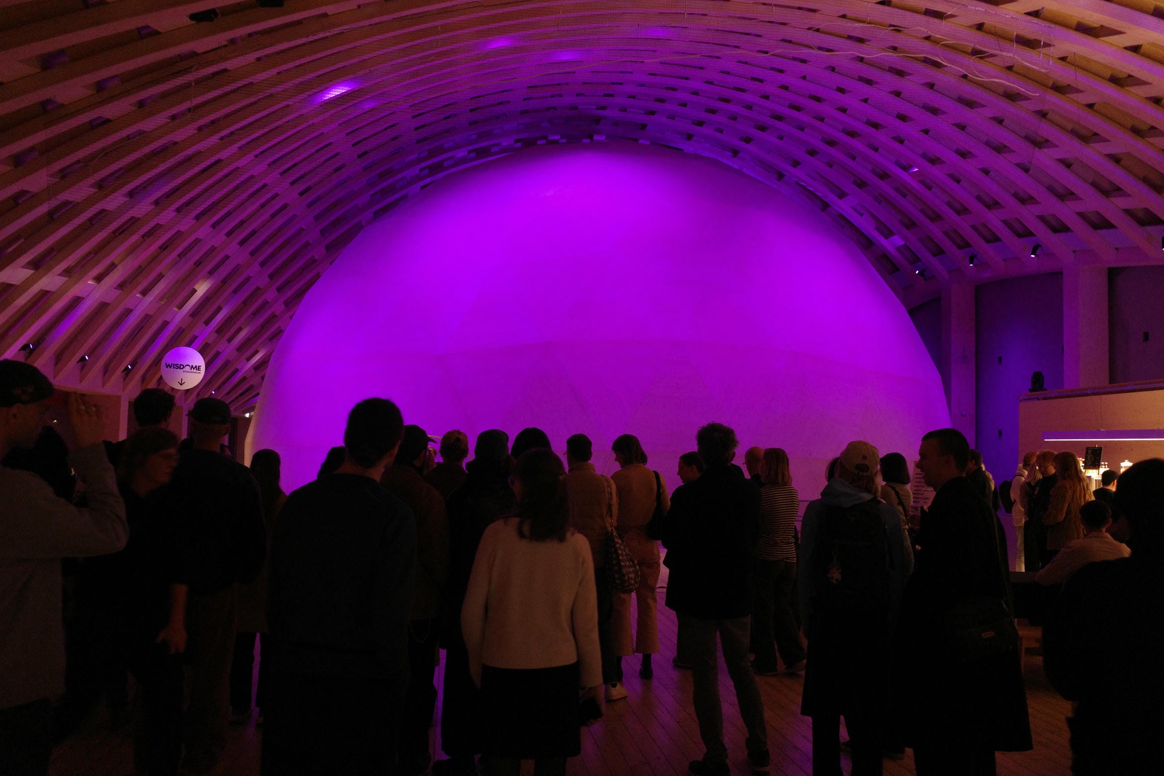 Crowd standing in front of a pink lit dome structure
