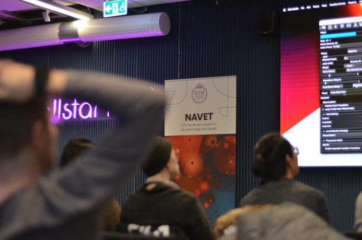 Crowd watching a presentation with a NAVET poster in the foreground