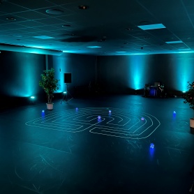 Blue lit room with a labyrinth in tape on the floor