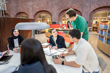 En lärare pratar med studenter runt ett bord
