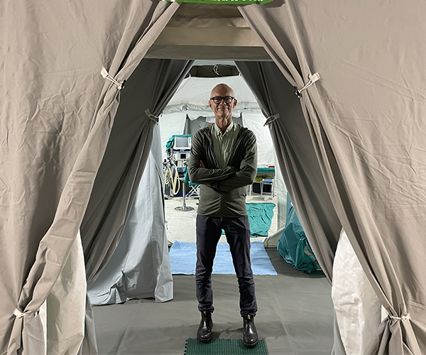 Johan von Schreeb står civilklädd  i ett fältsjukhus