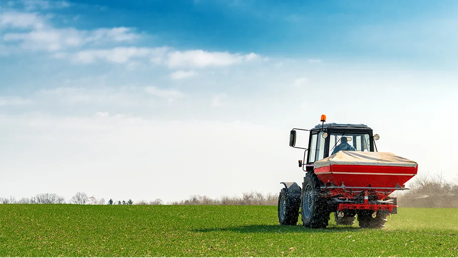 tractor spreading fertilizer on field