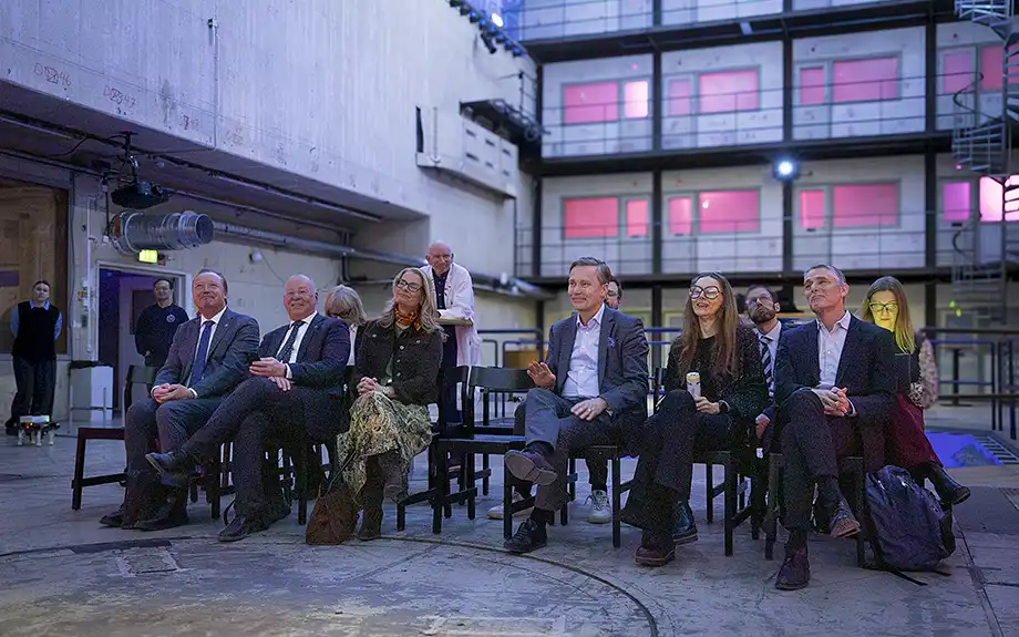 Människor i en publik tittar på skärm.