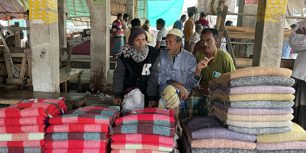 Three men selling recycled textiles on a bazar in Bangladesh.