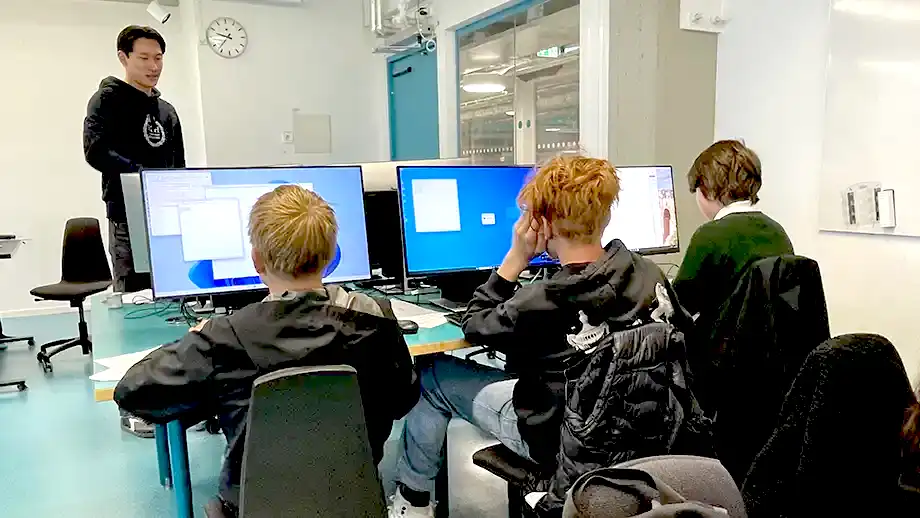 Tre elever framför skärmar samt en lärare