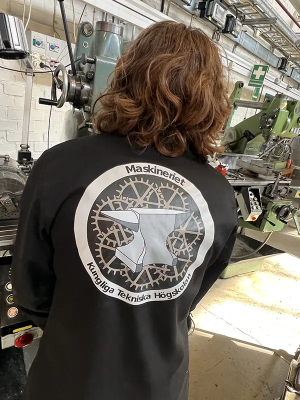 A student in the KTH Manufacturing Lab makerspace wearing a lab coat with the Maskineriet logo.