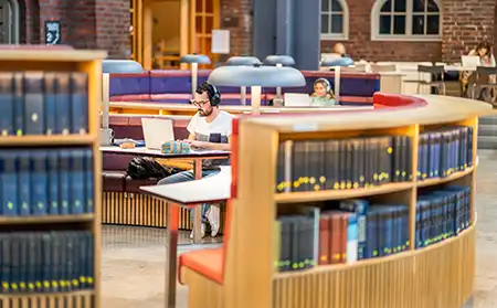 En person sitter och pluggar i biblioteket