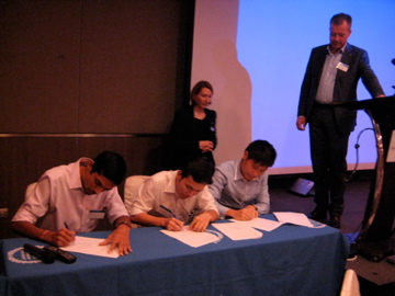 Avtalet signeras vid ett bord med en KTH duk. KTH:s rektor och alumnansvarig står bredvid. 