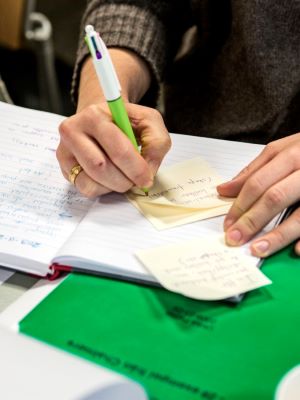 En person antecknar med skrivbok och post-it-lappar