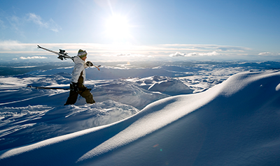 Skier carrying skis across snowy mountain top