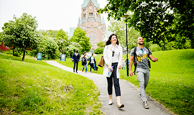 Students walking through a green park with a church in the background