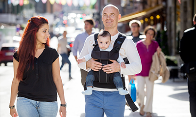 Family walking down the street, man having a baby in a baby carrier