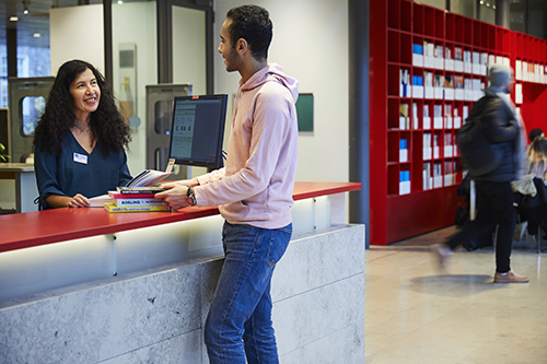 A librarian and a student at the service desk at KTH Library.