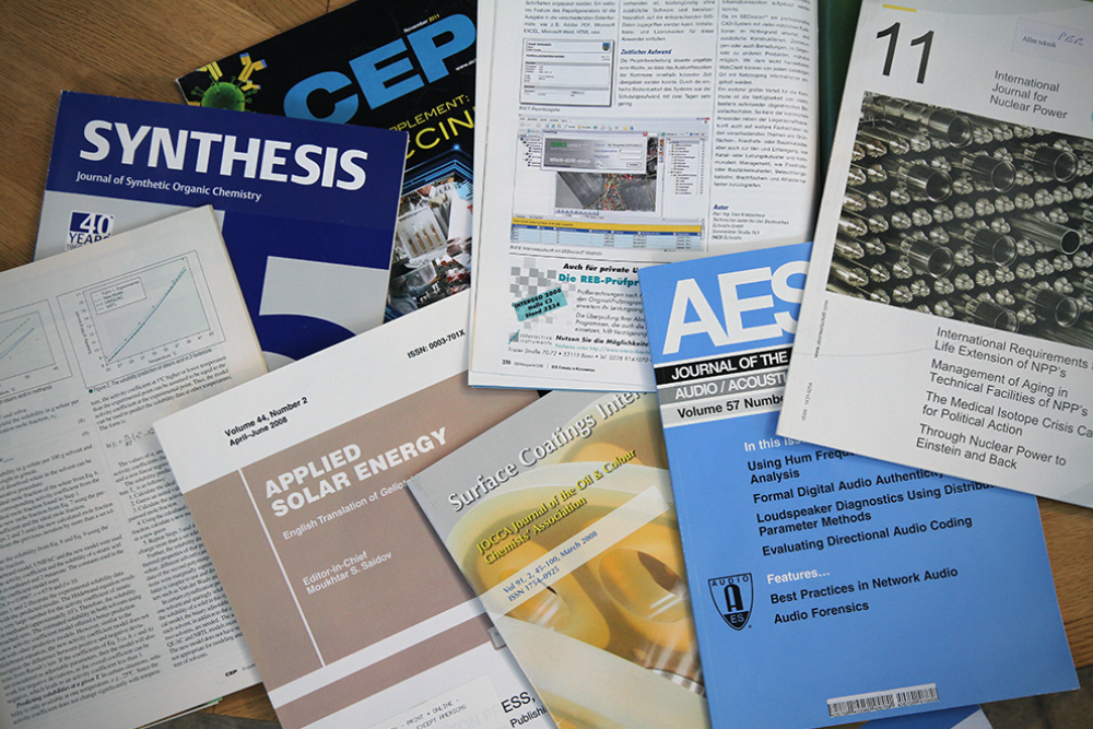 Ett flertal forskningstidskrifter utspridda på ett bord.