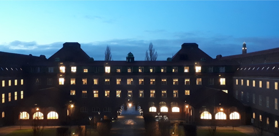 KTH main building in sunset with blue sky and lights from the windows.
