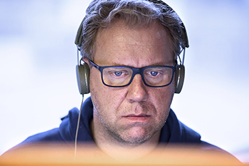 En man med hörlurar sitter koncentrerad och tittar på en datorskärm.