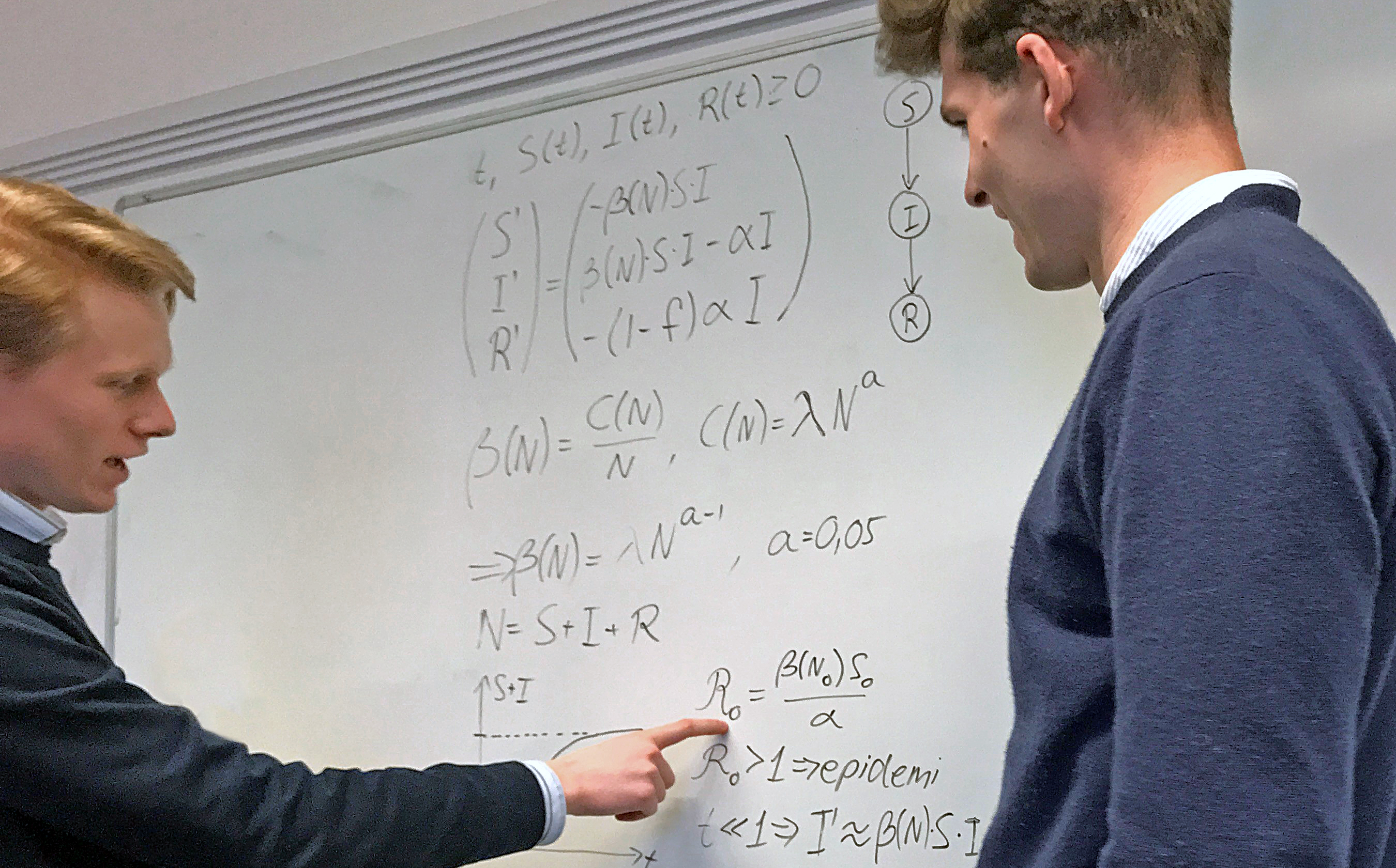 KTH-studenterna André Gerbaulet och Robin Sandström diskuterar koden bakom prognosverktyget. Detta gör de vid en whiteboardtavla där matematiska formler står uppskrivna.