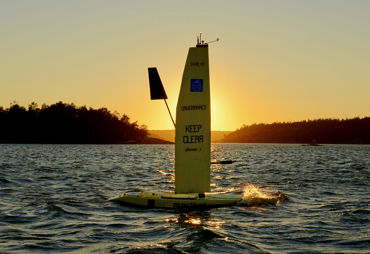 Den självseglande båten Maribot Vane från KTH i fin solnedgång på halvöppet vatten. Solen befinner sig precis bakom seglet. 