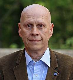 Porträttfoto föreställandes professor Ulf Olofsson. Han bär blå skjorta och kavaj och ler lite, lite. Blicken är allvarlig och fast och han bär en KTH-pin på ena kavajslaget.
